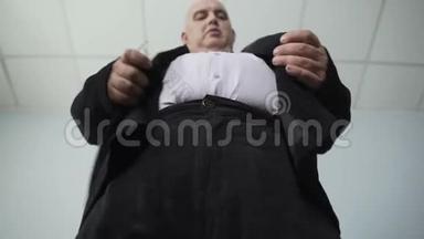 穿着经典西装的滑稽肥胖男子在夹克上系扣子，超重
